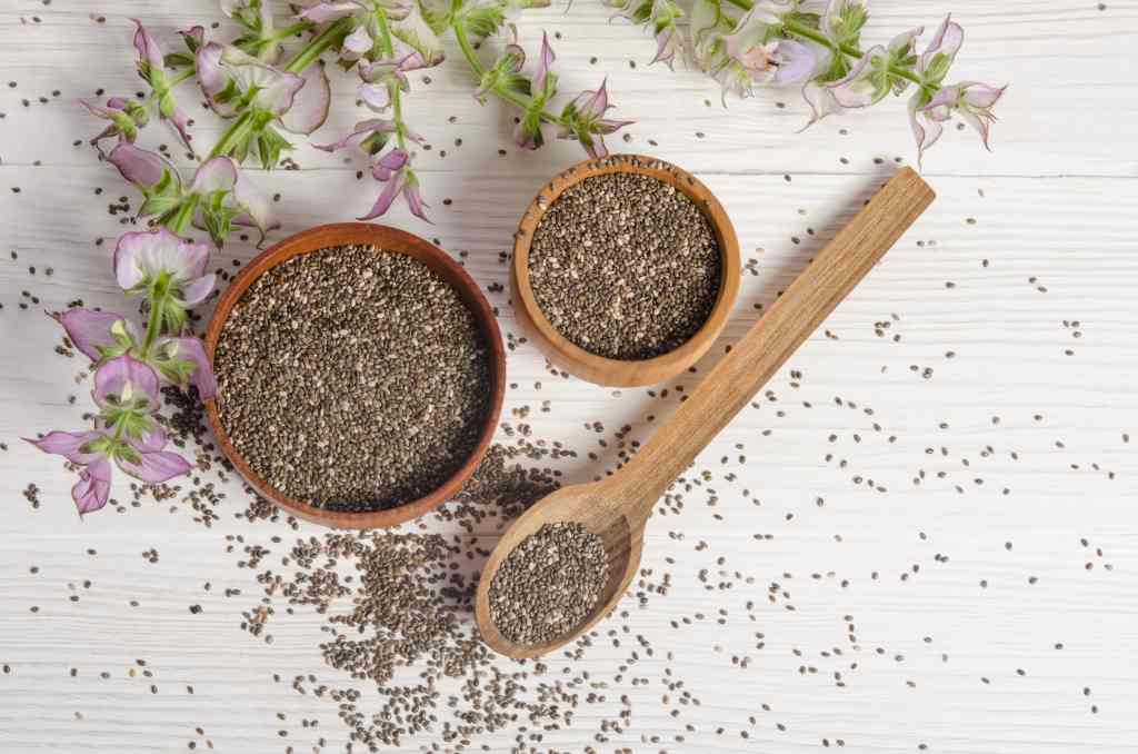 Chia seed healthy super food with flower over white wood background. Salvia hispanica.